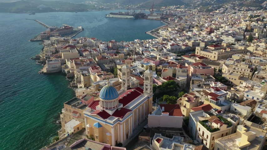 Aerial drone video of picturesque district built by the sea of Vaporia in main town of Syros or Siros island Ermoupolis and famous church of Agios Nikolaos, Cyclades, Greece