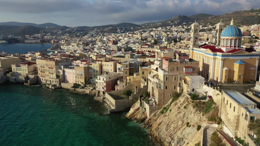 Aerial drone video of picturesque district built by the sea of Vaporia in main town of Syros or Siros island Ermoupolis and famous church of Agios Nikolaos, Cyclades, Greece