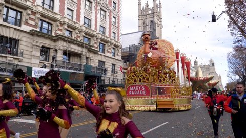 New York City, NY - November 28, 2019: Macy's Cheerleaders with pompoms dancing and marching along in the Thanksgiving Day Parade with throngs of spectators on the sides
