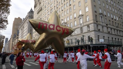 New York City, NY - November 28, 2019: Macy's Opening Golden Star Balloons in the Annual Thanksgiving Day Parade with masses of people on the sides on a beautiful Autumn Day