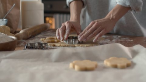 Close up of female baker hands making biscuits using baking tin in shape of flower