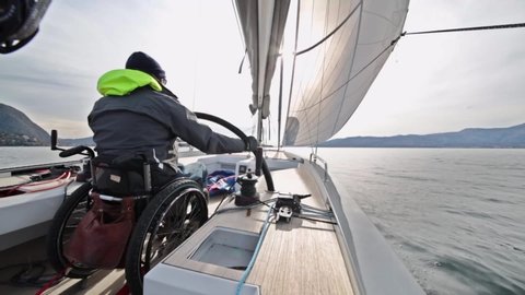 disable man on chair, driving sail boat
