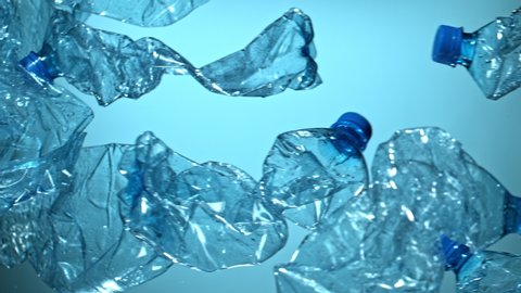 Super Slow Motion Shot of Flying Empty Plastic Bottles on Blue Gradient Background at 1000fps.