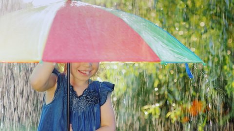 Funny girl hiding under an umbrella from the rain. Warm summer rain