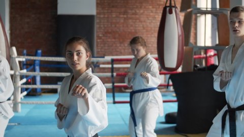 Panning of team of young kickboxers practicing together in fighting center