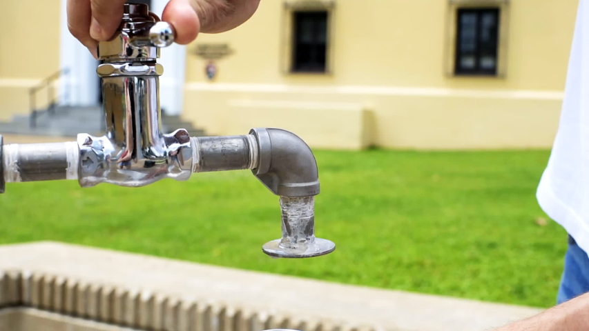 Hot Springs, Arkansas, USA bath house row with man hand on street in city closeup pouring mineral healthy water into bottle at fountain in slow motion