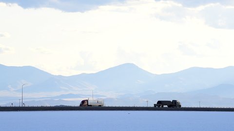 Wendover, USA - July 27, 2019: Bonneville Salt Flats landscape mountain view near Salt Lake City, Utah with clouds and trucks cars on highway