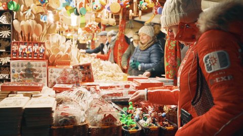Cracow, Poland - December 1, 2019: Traditional Christmas fair at main market square in Krakow, happy people walking between shop stalls looking for handmade gifts, sweets, food, toys and souvenirs