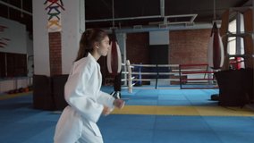 Tracking right of young barefoot female kickboxer wearing kimono kicking punching pillow the other female fighter holding in hands - Powered by Shutterstock - Get 15% off with code: PIKWIZARD15