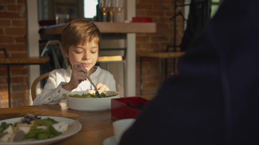 Father and son at lunch,boy stirs the salad with a fork