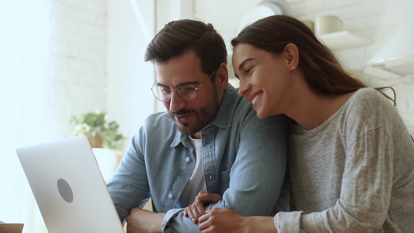 Head shot smiling family couple looking at monitor screen, watching comedian movie. Happy bonding loving wife sitting together with young husband in eyeglasses, shopping buying goods in online store. | Shutterstock HD Video #1042155769