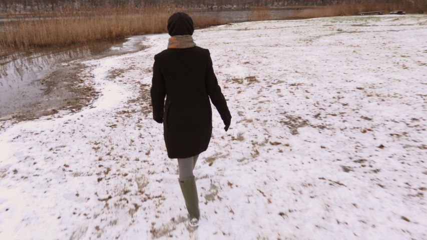 Happy woman walking on first snow and showing victory gesture
