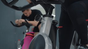 Beautiful focused woman exercising in cycling class. Close-up view of attractive brunette concentrated woman looking away while training on spin bike