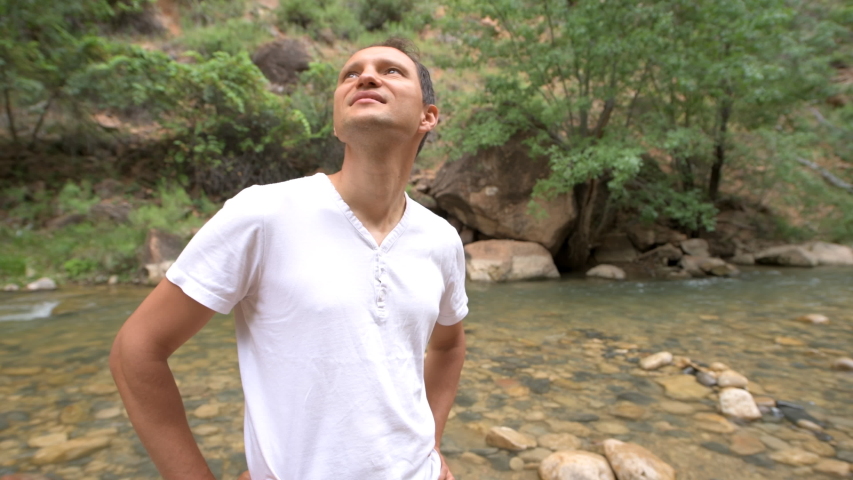 Zion National Park Riverside walk in Utah with closeup panning of man hiker on trail looking up on red canyon cliff formations near narrows