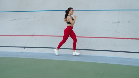 Fit girl running at cardio workout outdoor. Woman runner training on stadium track. Sport woman jogging on athletics track. Fitness woman running at sport stadium
