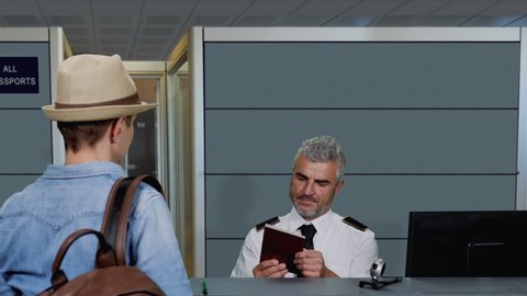 Airport security customs officer checks passport to a woman traveler passenger