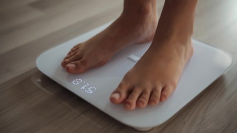 Female On Scales Measure Weight. Fit Girl Legs Step Bathroom Scale. Fitness Diet Woman Feet Standing Weighing Scales. Dieting Woman Checking BMI Weight Loss.  Barefoot Measuring Body Fat Overweight