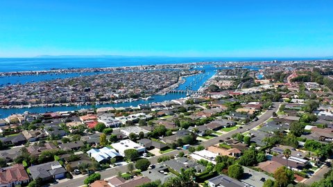 Aerial view of Balboa Island luxury coastal neighborhood in Newport Beach, Orange County, California with ocean and harbor below.