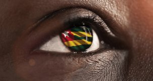 woman black eye in close up with the flag Togo in iris with wind motion. video concept