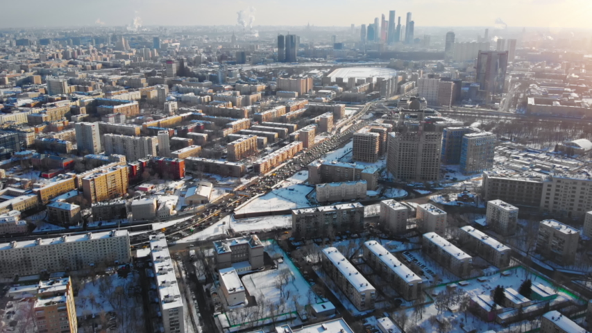 Beautiful aerial panorama of Moscow on sunny winter day. Picturesque view from above on the city covered with snow and lit by the sun, with buildings, traffic and Moscow City Business Center far away.