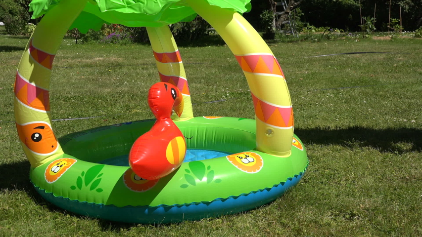 Mother habituate small child to rubber inflatable water pool outdoor in park. video clip.