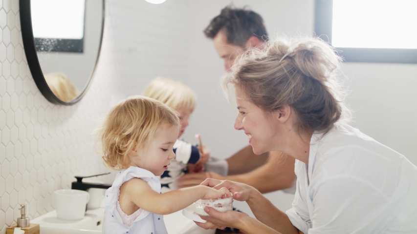 Young family with two small children indoors in bathroom, having fun.