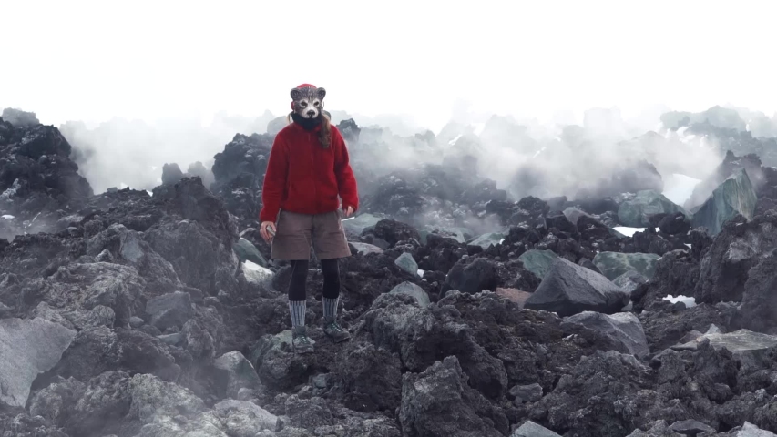 A woman in a bear mask standing next to an erupting volcano. Kamchatka