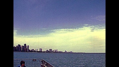 Chicago, Lake Michigan, Illinois, United States - Circa 1977: people on vacation in Milton Lee Olive Park, waterfront skyline of Chicago. Vintage dress 70s. Historical United States of America.