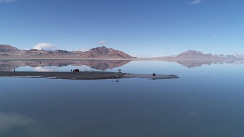 Rotating aerial view of water over the Bonneville Salt Flats as it reflects like a mirror around road dead ending in the lake.