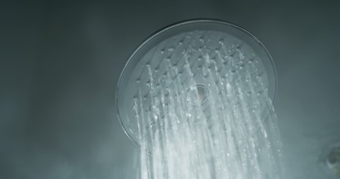 Cinematic macro shot of shower head with drops of hot water are falling down in slow motion.