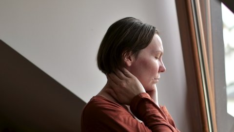 Woman with severe neck pain in loft apartment, selective focus