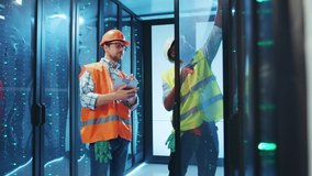 Diverse team of IT technicians fixing bugs and errors in server cabinet, using digital tablet and wearing high vis safety vests. Professional team. Data center. - Powered by Shutterstock - Get 15% off with code: PIKWIZARD15