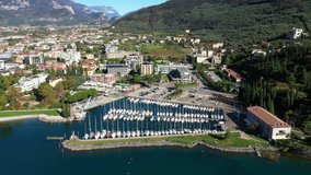 Aerial video with drone. Panoramic view of the alps Lake Garda and the city of Riva del Garda, Italy. Blue sky. Boat parking in the city.