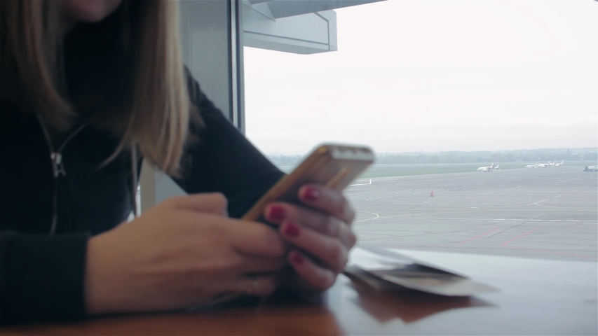 Happy girl waiting airport departure young smiling woman with smartphone passport and ticket closeup refocusing from runway background
