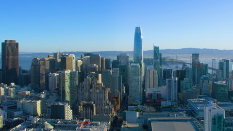 Aerial view of San Francisco skyline. Famous skyscrapers over a blue sky. Oakland Bay Bridge full of traffic. California, United States. Shot on Red weapon 8K.