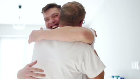 Happy father and son hugging when meeting at home after a long separation. Father retired and adult son, fathers day, happy family