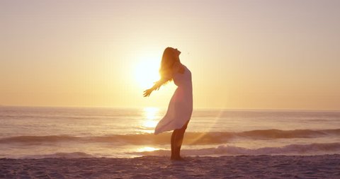 Free happy woman arms outstretched enjoying nature on beach at sunset face raised towards sky slow motion RED DRAGON