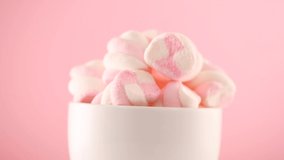 Marshmallow. Close-up of Marshmallows colorful chewy candy, rotation over pink background. Sweet food dessert in a cup with hot chocolate close-up. 4K UHD video.