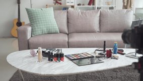 Cosmetic set on light living room table at home. professional camera on tripod ready for live streaming of makeup beauty video blog. make up palette and colorful nail polish on desk in apartment.