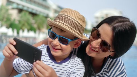 Close-up happy travel family laughing taking selfie using smartphone near swimming pool