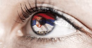 woman green eye in close up with the flag Serbia in iris with wind motion. video concept