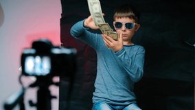 Teenager millionaire video blogger makes blog about making money. Holds lot of US dollars in hands throws them. Tips passive income streams stability generating income through dividend stocks. People - Powered by Shutterstock - Get 15% off with code: PIKWIZARD15