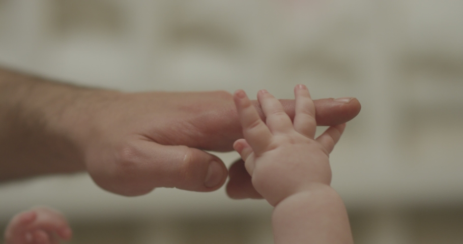 Close-up shot of baby's little cute hand reaching for father's loving finger . Baby holding parent's finger . Parent holding newborns hand in Slow Motion . Hand in hand. Father and his newborn baby .  | Shutterstock HD Video #1042264066