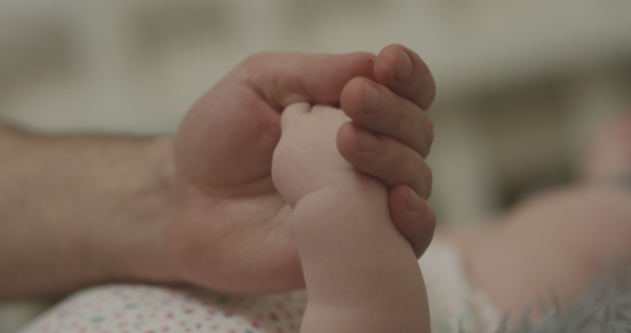 Close-up shot of baby's little cute hand reaching for father's loving finger . Baby holding parent's finger . Parent holding newborns hand in Slow Motion . Hand in hand. Father and newborn baby .  | Shutterstock HD Video #1042264078