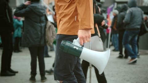 Man walk and hold megaphone in hand and shouting closeup. Human rights. Crowd people day demonstration. Rebel go shout loudspeaker strike protest close up. Revolution in city street. Political rally.