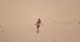 Aerial view Video of young woman lying on the ocean beach near beautiful waves 