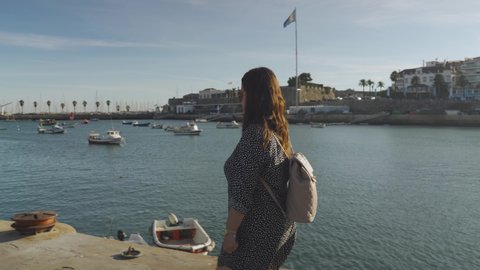 Tracking shot of white woman walking in a Deck at Ribeira Beach, in Cascais, Portugal.