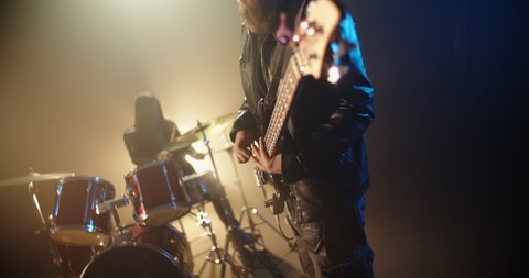 An authentic rock band is playing music in a club, guitarist and drummer rocking the party up together - rock band music concept 4k footage