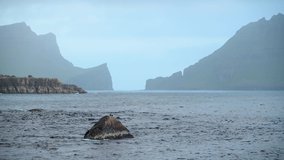 Dramatic view on Drangarnir and Tindholmur sea stacks in Atlantic ocean from Gasadalur village on Vagar island, Faroe Islands. UHD 4k video