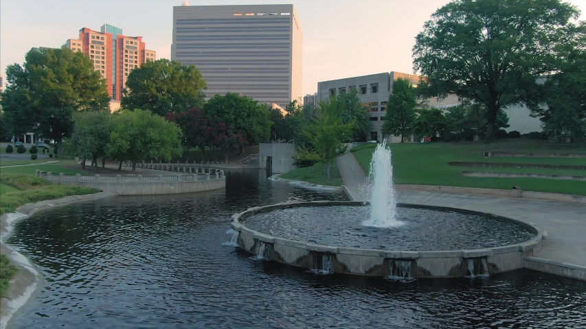 Aerial: flying over pond & fountain in Marshall Park in downtown Charlotte. North Carolina, USA. 